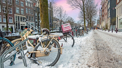 Snowy city Amsterdam in the Netherlands in winter at sunset