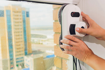 Vacuum cleaner robot cleaning window in high building outdoor.