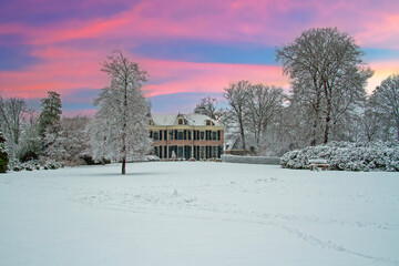 Snowy historical country house in winter in the Netherlands at sunset