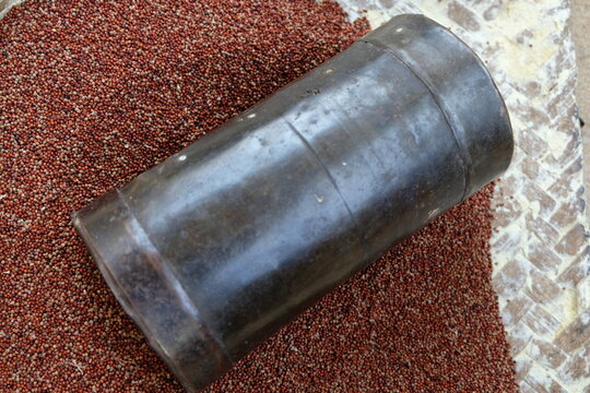 Pile of red millets also known as ragi along with measuring pot.	
