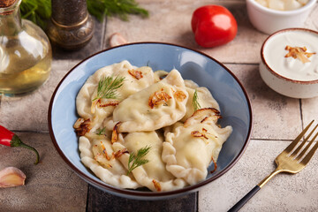 Dumplings, pierogi or vareniki with potato or meat filling. Served with dill, roasted onion and sour cream sauce. Polish or Ukrainian cuisine. Delicious homemade dish.