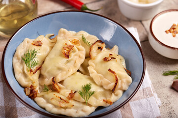 Dumplings, pierogi or vareniki with potato or meat filling. Served with dill, roasted onion and sour cream sauce. Polish or Ukrainian cuisine. Delicious homemade dish.