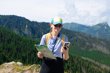 Shot of a young lost woman holding a map while taking in the view from the top of a mountain. Woman...