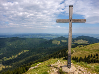 Holzkreuz auf Gipfel mit Blick über hügelige Allgäuer Landschaft