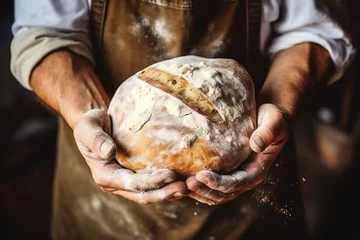 Tuinposter Baker holding a loaf of freshly baked bread in his hands © duyina1990