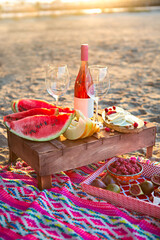 Beach picnic with rose wine, fruits, nuts meat and cheese