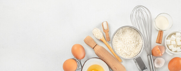Ingredients for baking eggs, flour, sugar, butter, milk and rolling pin on light table. Long banner format. top view. copy space for text