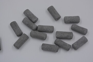 Unusual branded factory gummy candies in the form of gray, metal cylinders, capsules, talismans located on a white background.