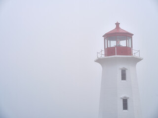 The beautiful Peggys Cove Lighthouse on the coast of Nova Scotia in thick fog