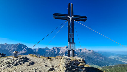 Fototapeta na wymiar Summit cross of mount Hornischegg (Monte Arnese) in Carnic Alps, border Austria Italy, EU. Scenic view of mountain peaks of untamed Sexten Dolomites, South Tyrol. Blue sky. Wanderlust concept in Alps