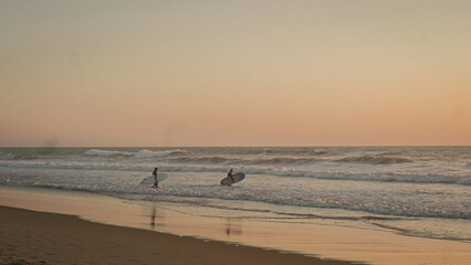 Fototapeta na wymiar sunset on the beach with surfers