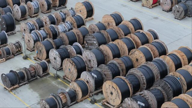 Drone captures the ordered arrangement of wooden cable drums in an outdoor storage space. Overcast weather.