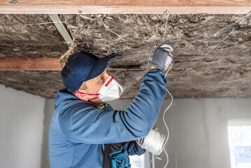 Ceiling insulation. The Worker fixing a thermal insulation from a glass wool inside the wooden frame using a twine.