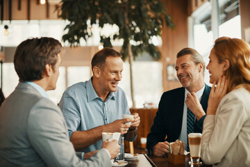 Happy diverse business people laughing in cafe