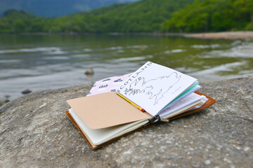 Journalling-open book left on rock overlooking lock in Scotland , open at a drawing of the UK and waiting to be written in. Journalling is a popular hobby loved my many. 