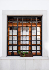 Window with iron grating on white wall. Lattice on the window, architecture of a country house. Window bars