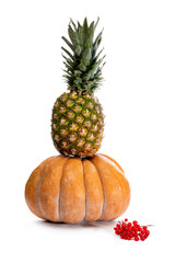 Pineapple on top of a pumpkin on a white background with viburnum