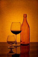 Still life with a bottle and glasses on a brown background
