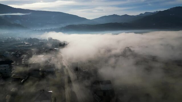 A drone flies over a mountain village covered in morning fog