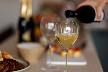 Close-up of an elegant glass with a long stem with champagne. The process of pouring sparkling wine into a goblet.