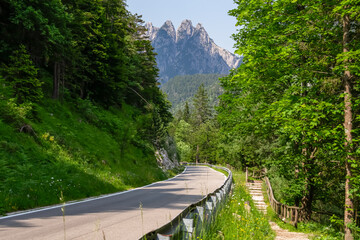 High alpine road along Lake Predil with panoramic view of majestic mountain peak Cinque Punte,...