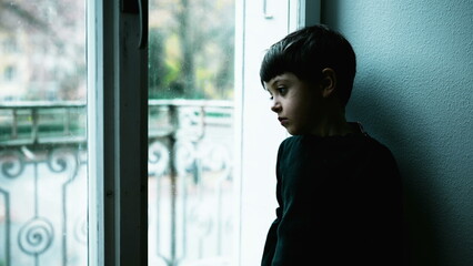 One young boy struggles with mental illness at home with green tint color. Child depressed standing...