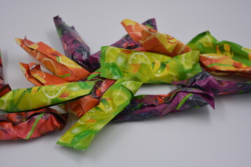 Bright, colorful factory candies on a stick packed in colored and bright packaging arranged on a white background.