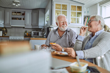 Happy senior couple eating breakfast in kitchen