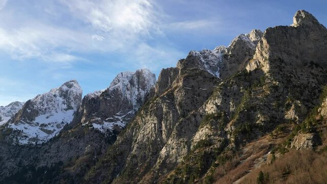 The drone flies along a mountain range with epic snowy peaks