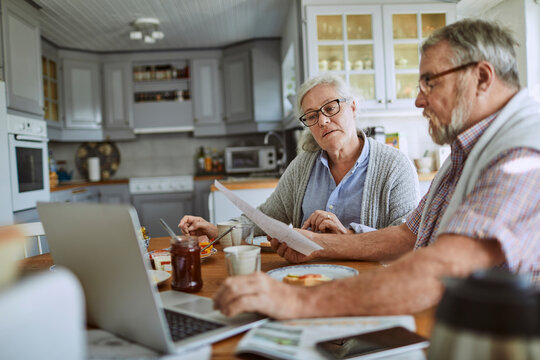 Senior couple going over bills at kitchen table