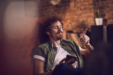 Young man listening music on headphones at home