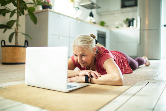 Senior woman doing yoga at home with laptop