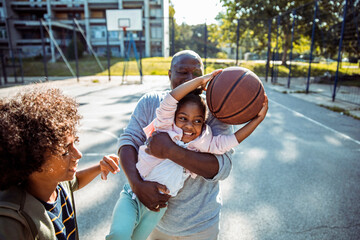 Family playing basketball together on an outdoor court