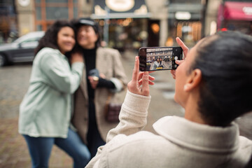 Young female friends taking a photo with smartphone on city street