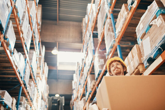 Young Man Carrying Box In Large Warehouse