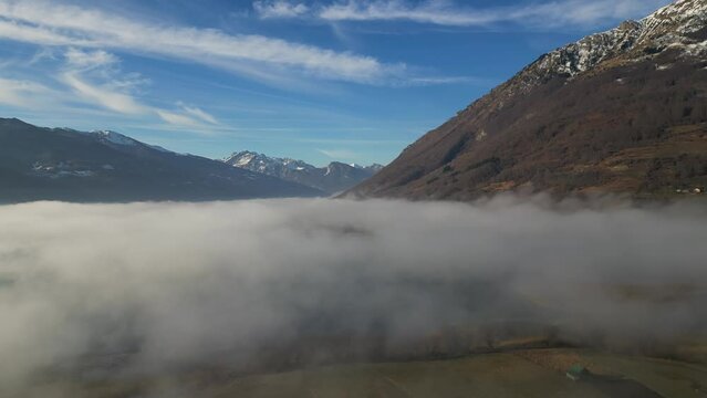 A drone flies over fields and lakes covered with thick morning fog