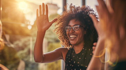 Joyful woman with glasses, smiling widely and giving a high-five, indicating a positive interaction or celebration