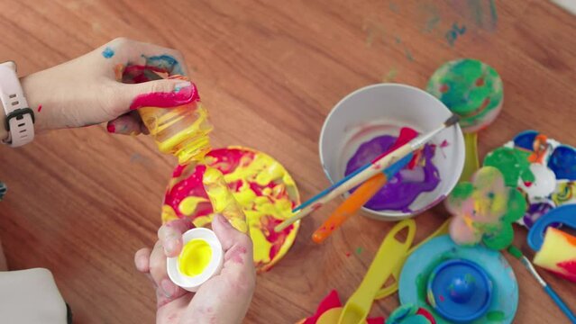 Top view of Asian Woman mixing colorful paints with painting equipment for prepared for painting with her son.