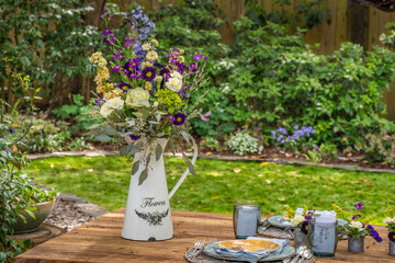 Garden scene for outdoor entertaining and decoration. Watering Can and pitcher, flowers, garden themed Spring and Summer scene for the residential home backyard