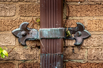 Closeup detail of a brown rain spout with ornate metal clasps, exterior home and garden design