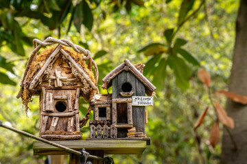 Closeup of garden bird houses made of twigs with depth of field greenery in the background