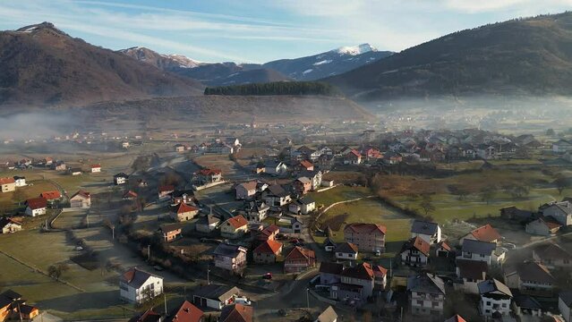 A drone flies over a mountain village covered in morning fog