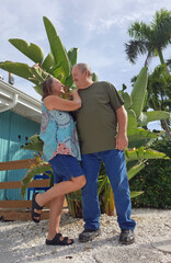 senior adult couple standing in front of house
