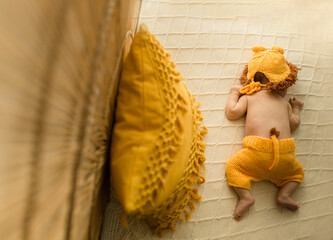 Baby liegt auf der Decke verkleidet als Löwe