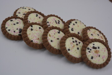 Delicious branded, factory-made, chocolate chip cookies with white fudge, fruit pieces, chocolate pieces arranged on a white background.