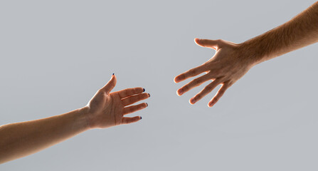 Hands man and woman reaching to each other, support. Giving a helping hand. Hands of man and woman on gray background. Lending a helping hand. Solidarity, compassion, and charity, rescue