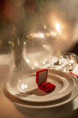 holidays, valentine's day and proposal concept - close up of engagement ring in red box on served...