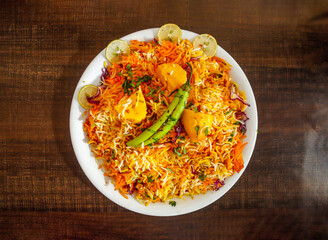 Aloo biryani rice with potato and lemon slice served in plate isolated wooden background top view indian spices and pakistani food