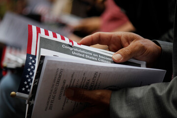 Close up detail of an immigrant's hand as he holds official welcome documents during the...