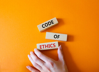 Code of ethics symbol. Concept words Code of ethics on wooden blocks. Beautiful orange background....